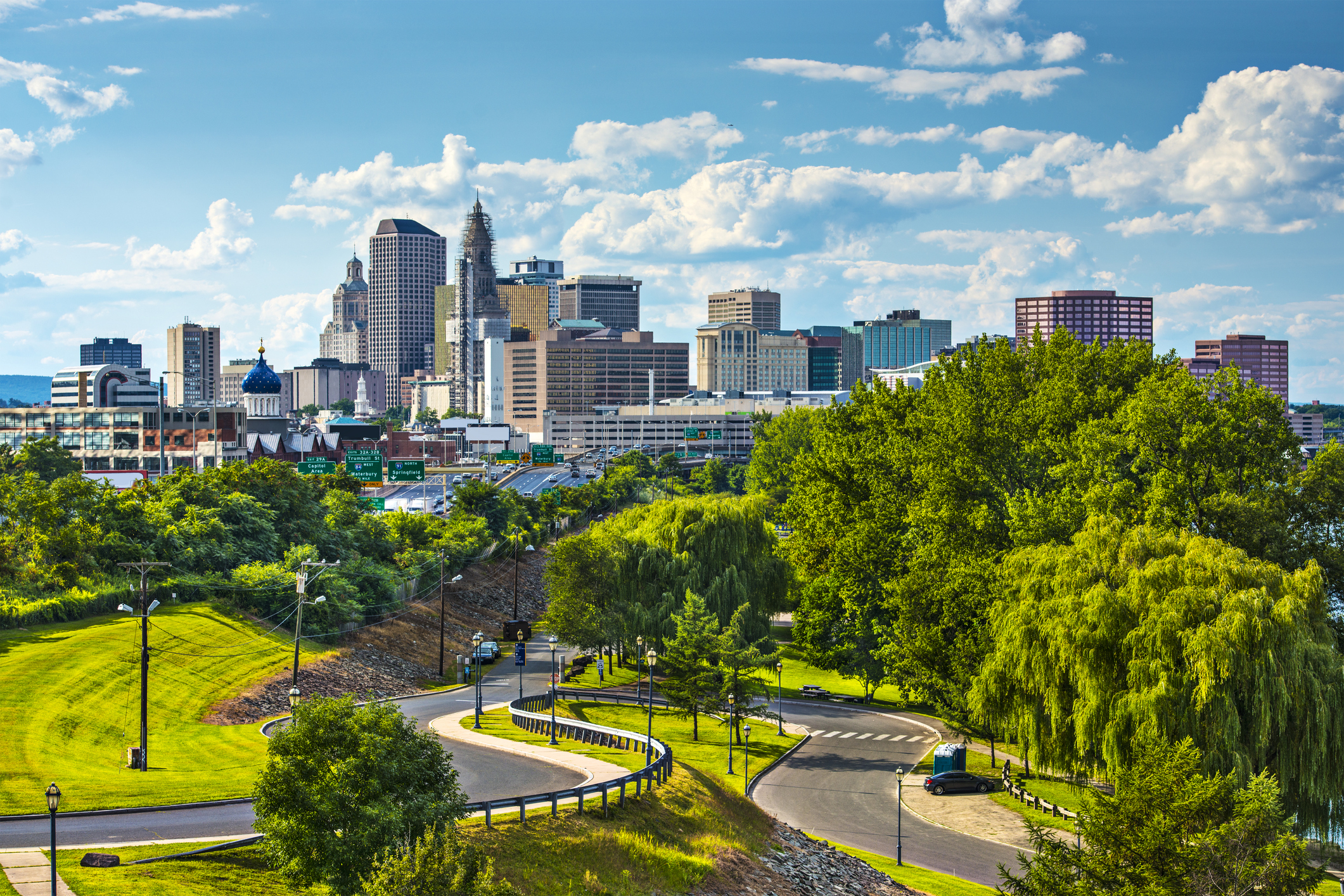 Hartford Connecticut skyline with downtown buildings and green park space on a sunny day