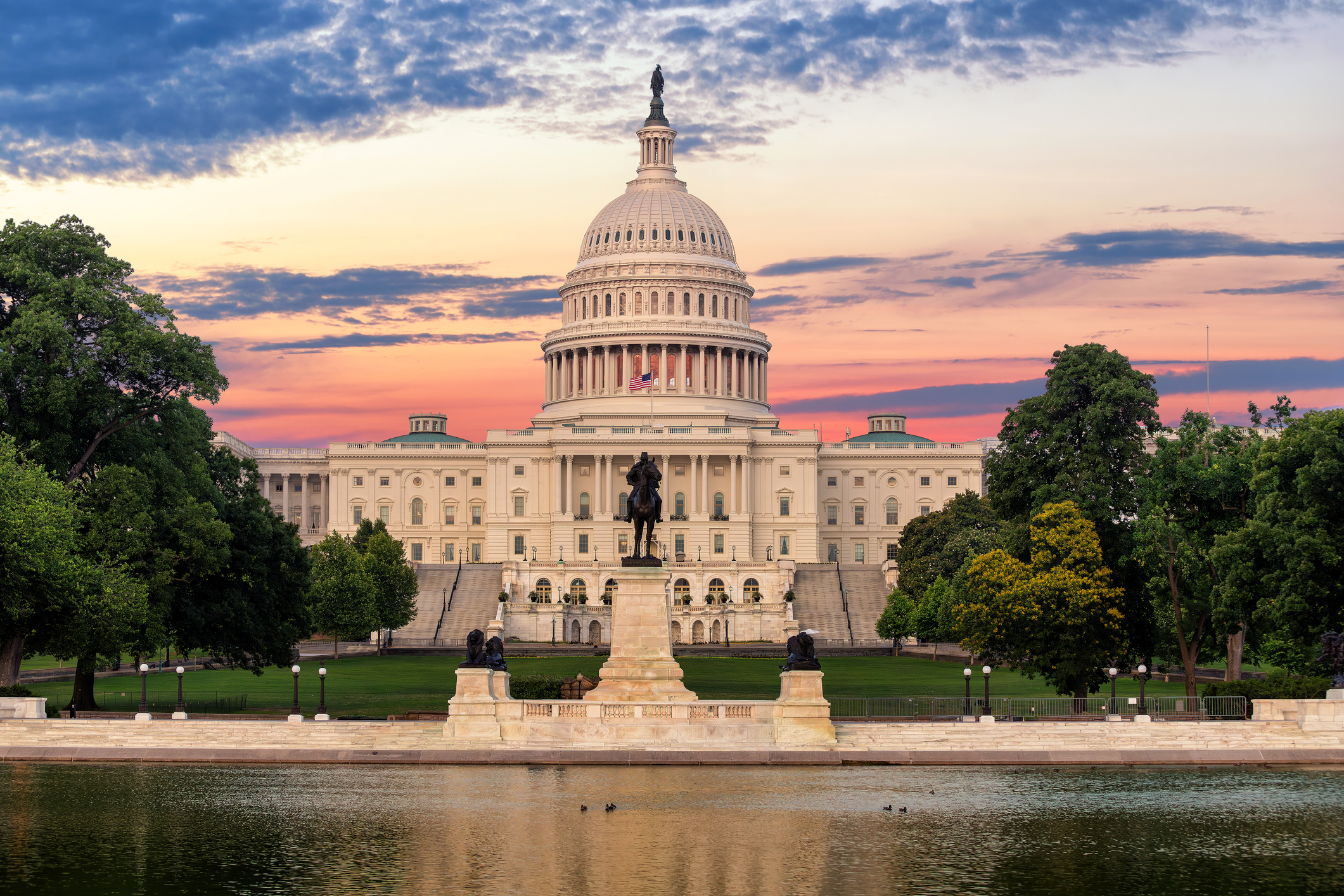 U.S. Capitol Building in Washington, D.C. at sunset with the reflecting pool in the foreground