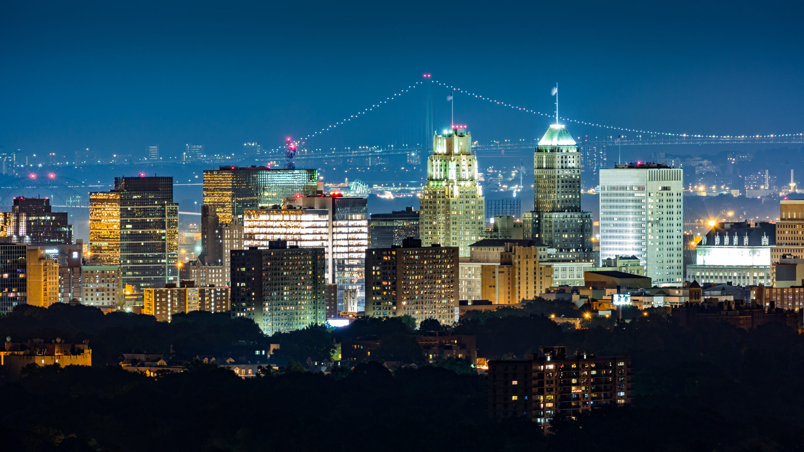 Newark New Jersey skyline illuminated at night with city lights and the George Washington Bridge in the background