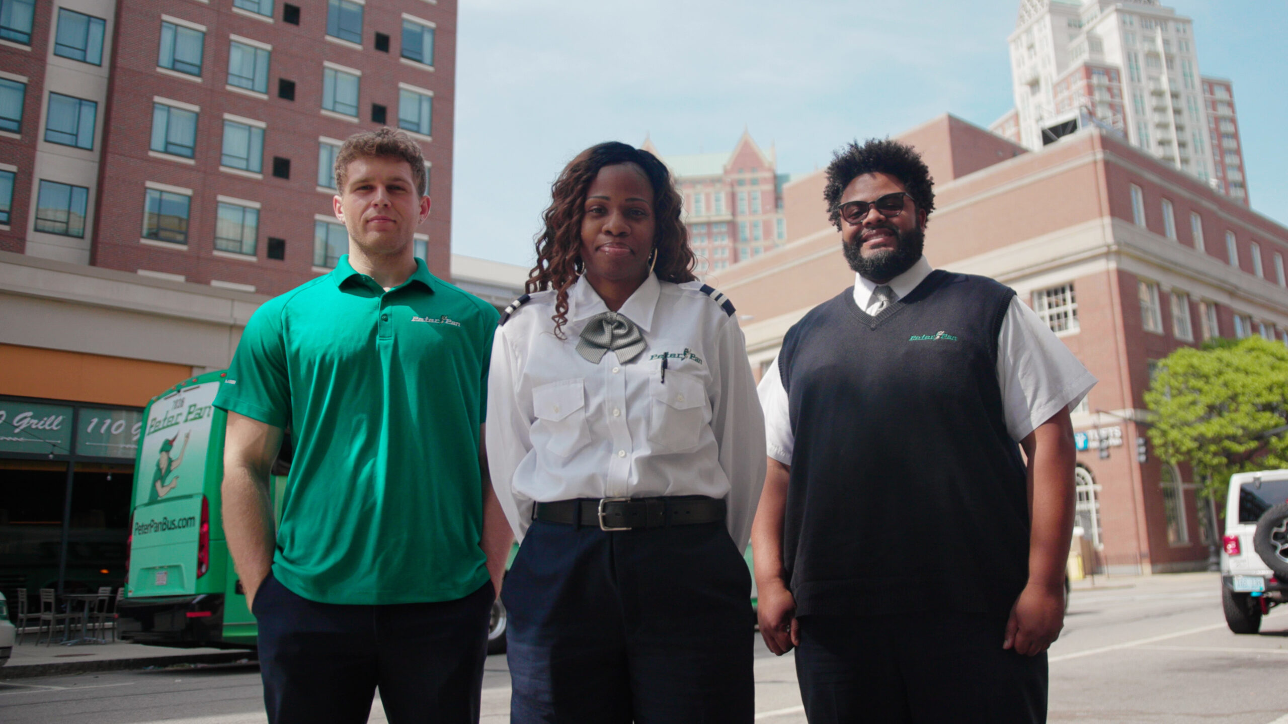 Peter Pan Bus Lines drivers and staff walking together in uniform with a company bus behind them, showcasing career opportunities.