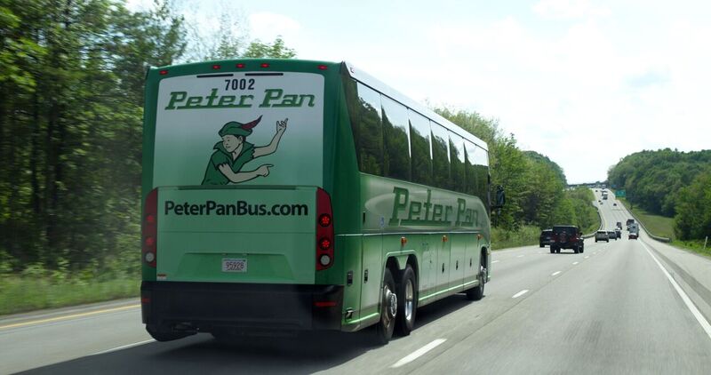 A Peter Pan Bus cruising along the highway—offering a smooth, affordable ride from Baltimore to New York City with no tolls, traffic stress, or parking costs.